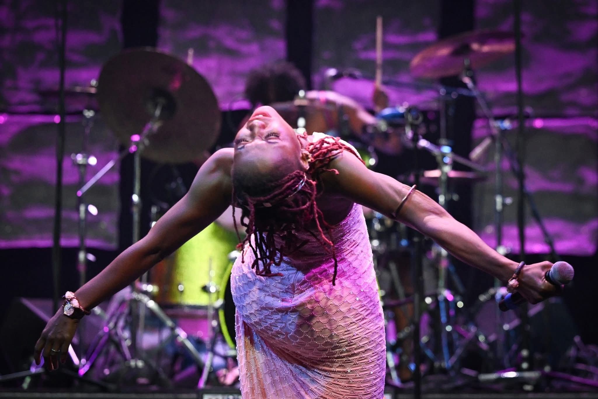 Tierinii Jackson Naftaly performing in pink dress, arm raised